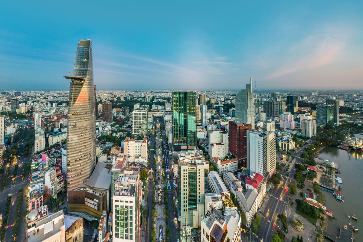 Bitexco Financial Tower dominates the skyline of Ho Chi Minh City at dusk, with the Saigon River visible.
